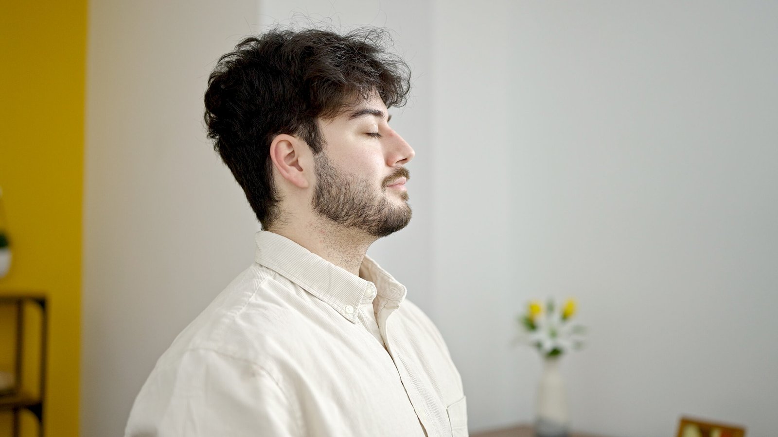 Hombre practicando una técnica de respiración con los ojos cerrados en casa